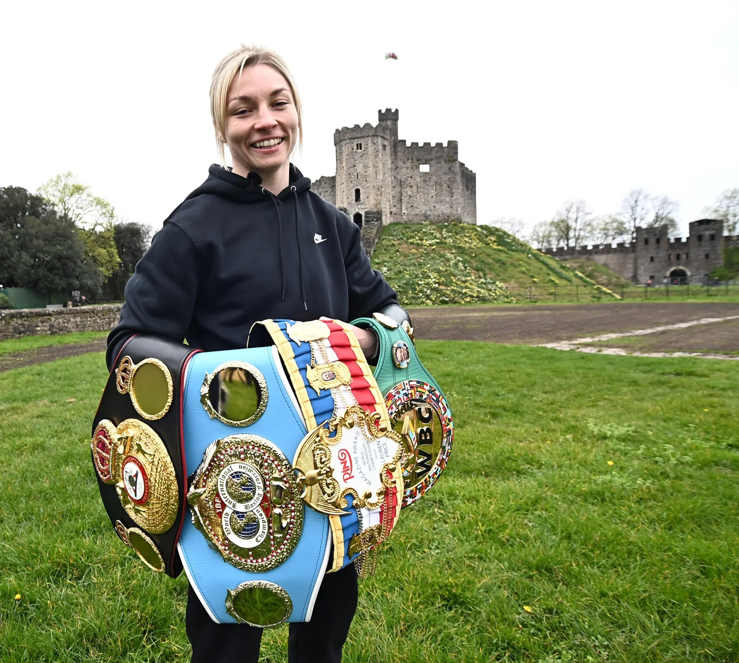 Lauren Price holding championship belts outside Cardiff Castle
